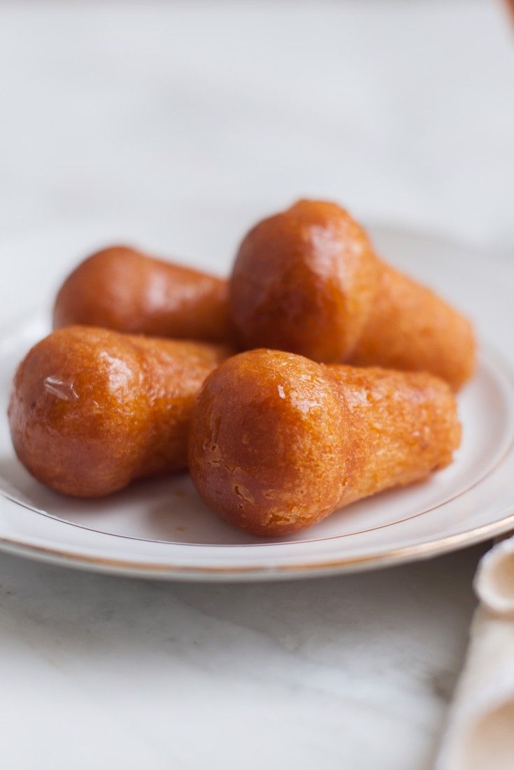 four donuts on a white plate sitting on a table