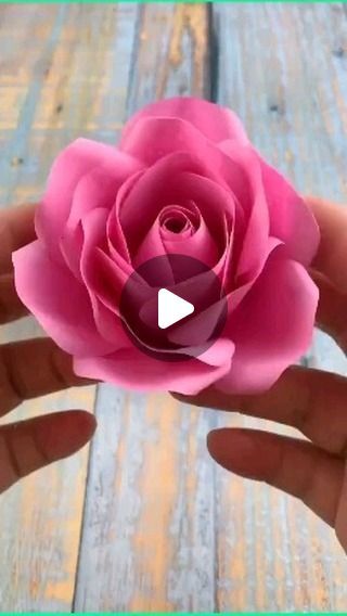 a person holding a pink flower in their hand on a wooden surface with text reading how to make paper flowers