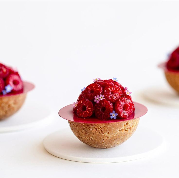 raspberries are placed on top of small desserts