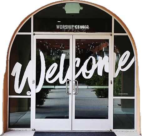 a welcome sign is on the front door of a building that has glass doors and windows