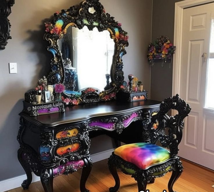 a black vanity with a colorful stool and mirror on it in a room that has hardwood floors