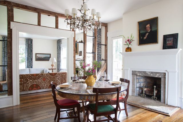 a dining room table with chairs and a chandelier in front of a fireplace