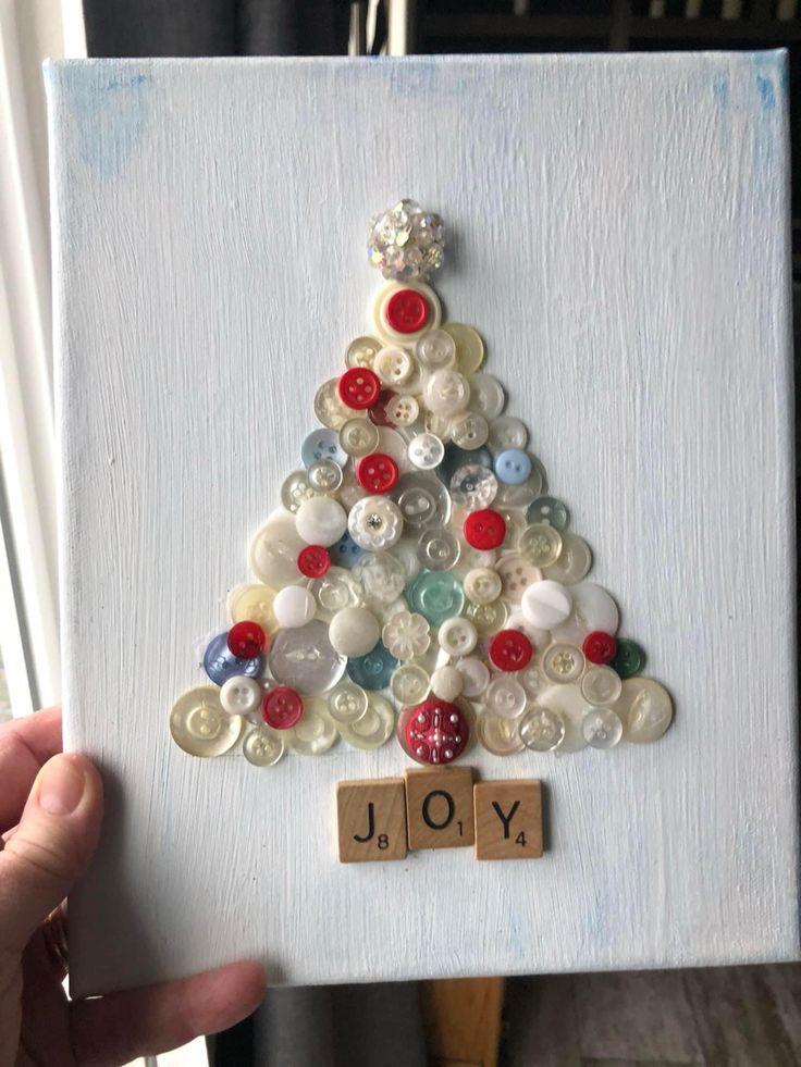 a christmas tree made out of buttons is displayed on a white board with the word joy spelled