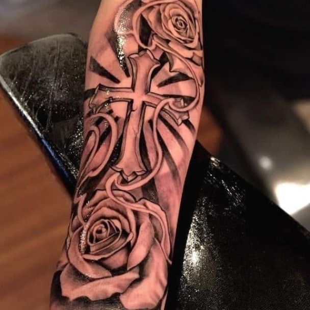 a person with a cross and roses tattoo on their arm