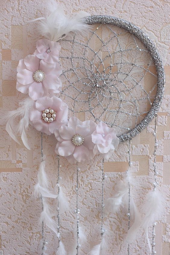 a dream catcher with flowers and feathers on a wall