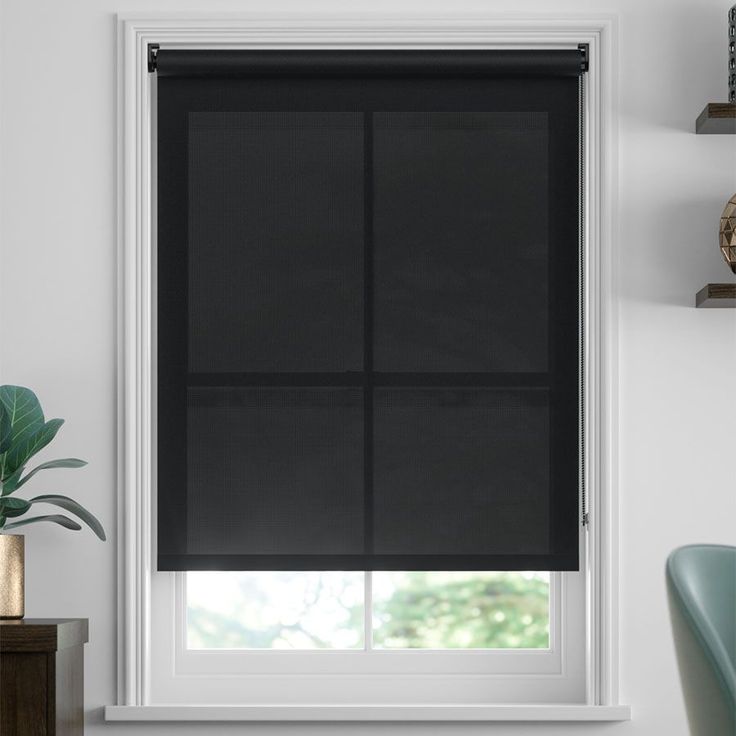 a black roller shade in a white room with a potted plant on the window sill