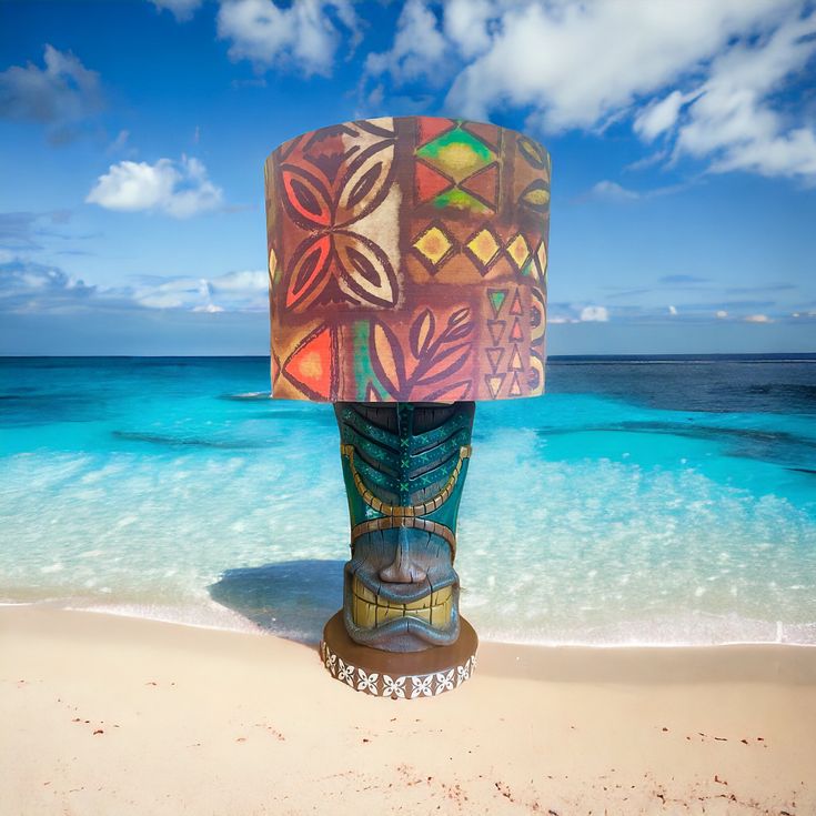 a sculpture is on the beach with blue water