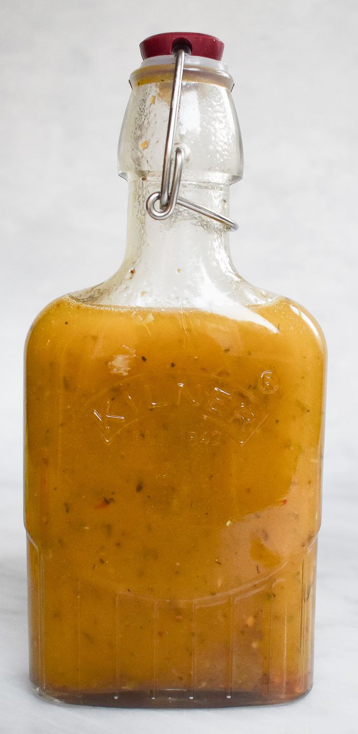 a glass bottle filled with mustard sitting on top of a table