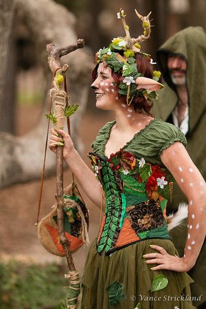 two people dressed up in costume and one is holding a bird on a stick while the other looks at something