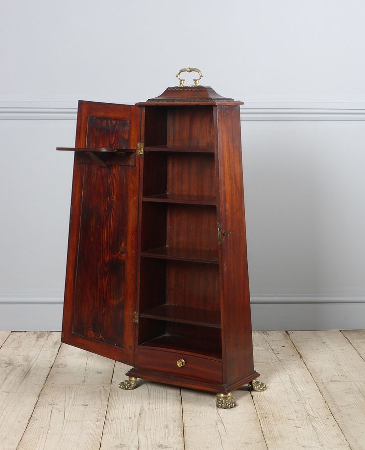 an old wooden cabinet with its door open on the floor in front of a white wall