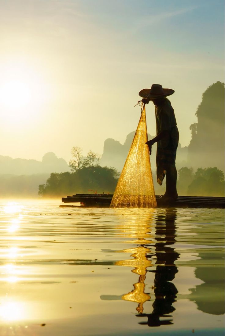 a man standing on top of a body of water with a net in his hand