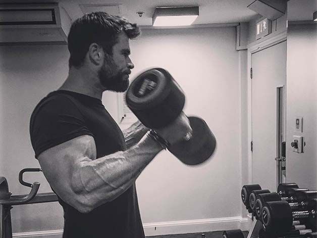 a man is in the gym with his arm wrapped around a punching mitt and looking off into the distance