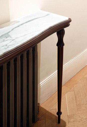 a marble top console table in the corner of a room next to a radiator