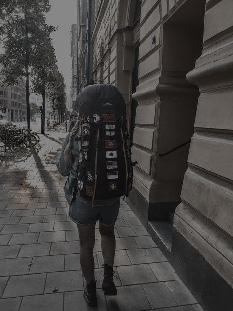 a woman is walking down the sidewalk with her back to the camera and she has a backpack on her shoulder