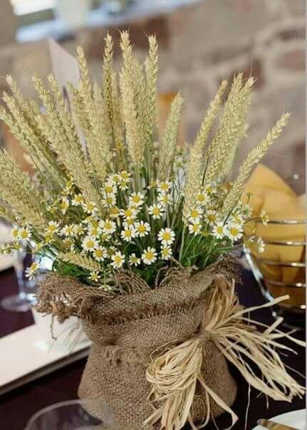 a vase filled with lots of white flowers on top of a table covered in burlock