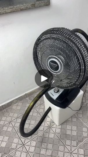 a black and white fan sitting on top of a tile floor next to a wall