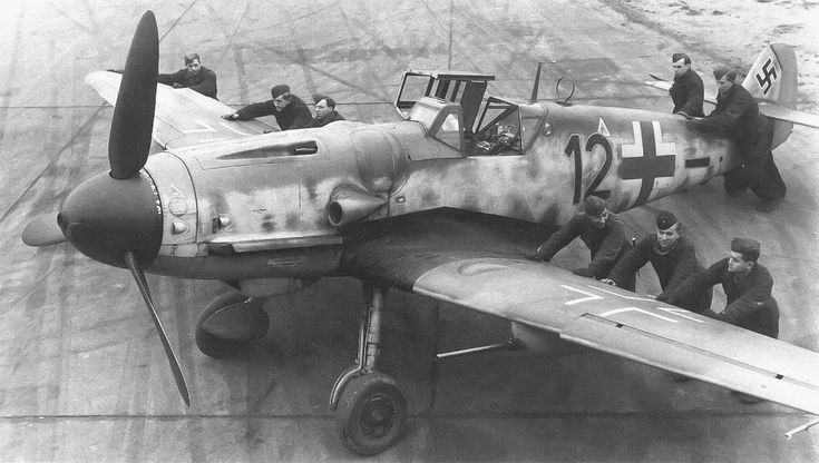 an old black and white photo of men standing around a fighter plane on the tarmac