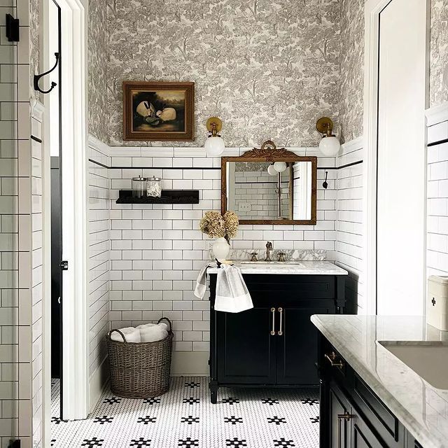 a bathroom with black and white tile flooring and wallpaper, along with a large mirror above the sink