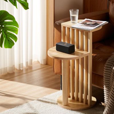 a small wooden table with a magazine on it next to a couch and potted plant