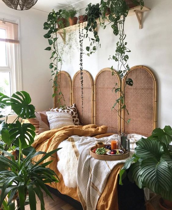 a bed with plants hanging from the headboard and pillows on it's sides