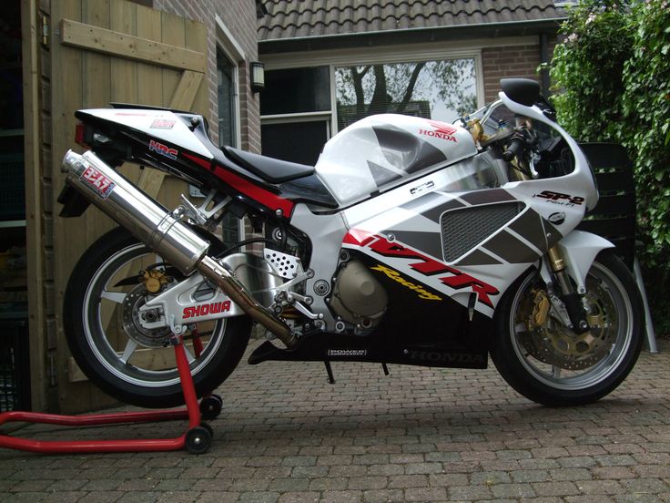 a white and red motorcycle parked in front of a garage with a brick walkway next to it