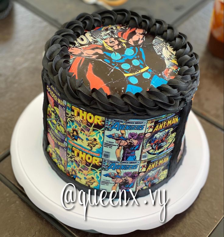 a cake with comic covers on it sitting on top of a white plate and black icing