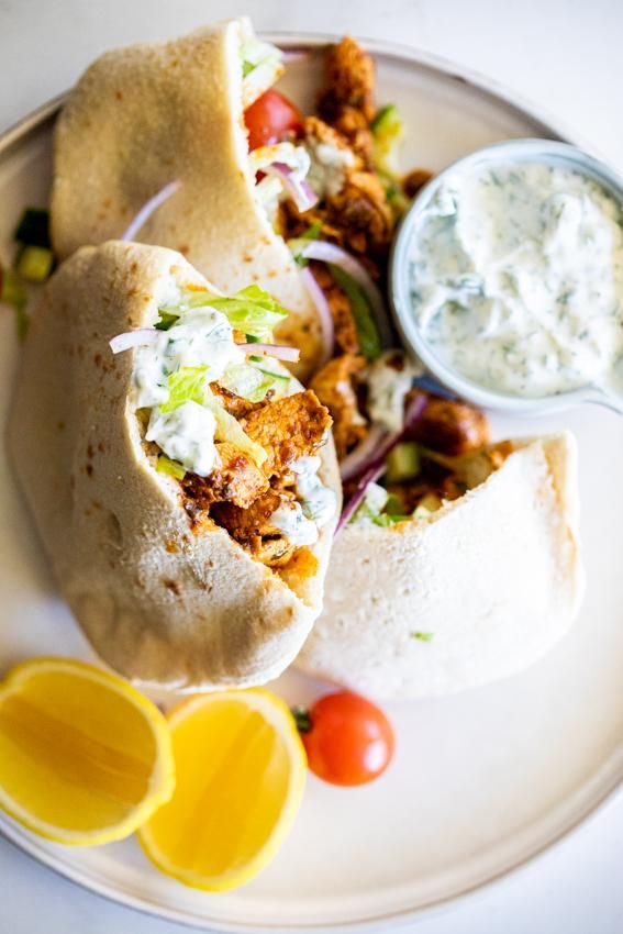 two burritos on a white plate with salsa and lemon wedges