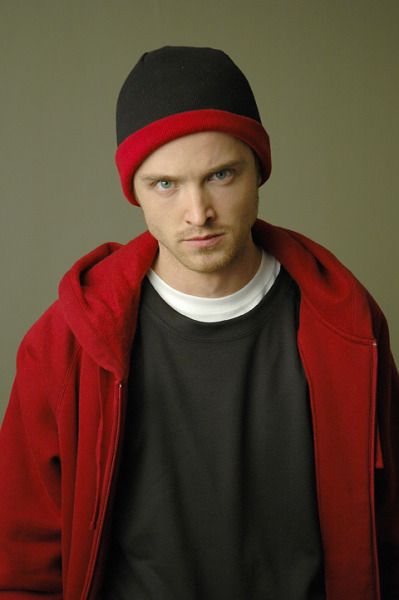 a young man wearing a red jacket and black shirt with a beanie on his head