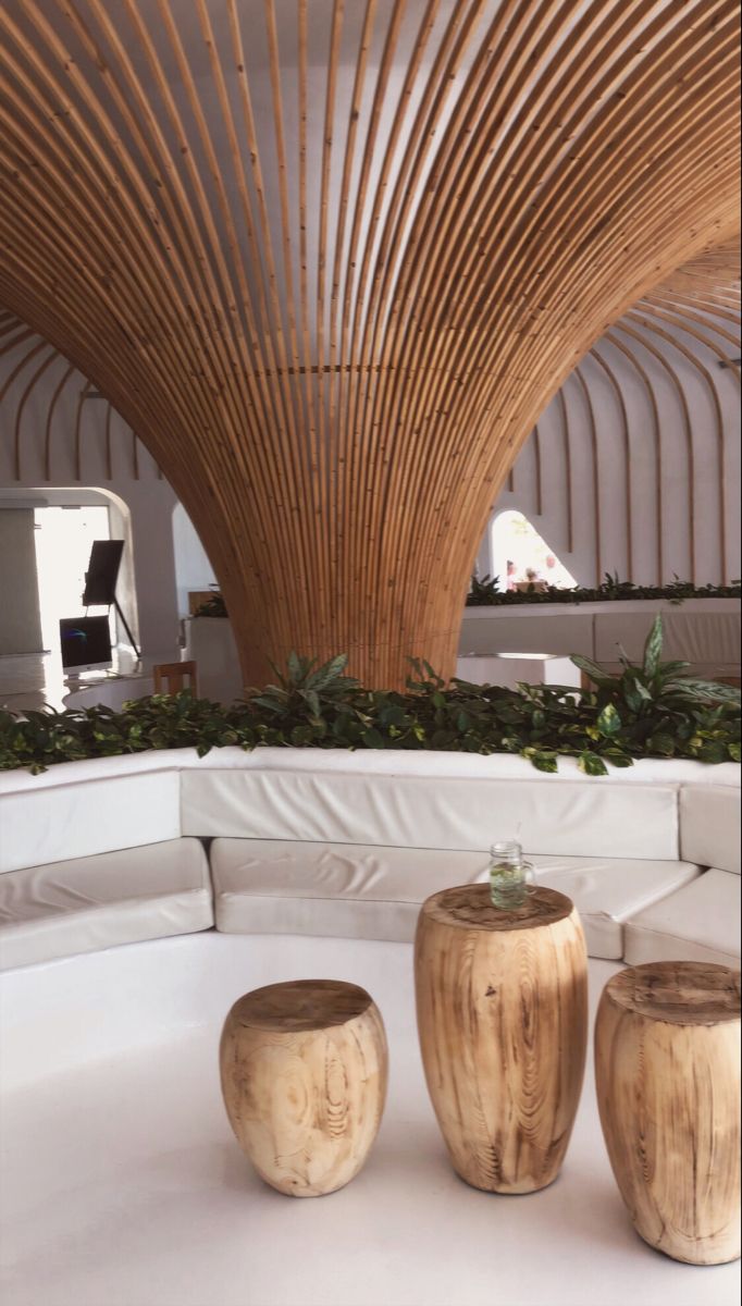 three wooden stools sitting on top of a white couch in a room with wood ceilinging