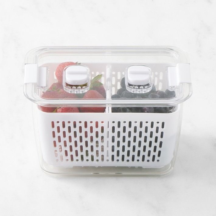 two plastic containers filled with fruits and vegetables on a white counter top next to each other