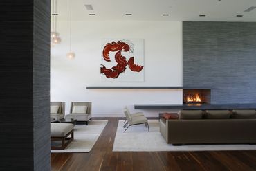 modern living room with wood flooring and large painting on the wall above the fireplace