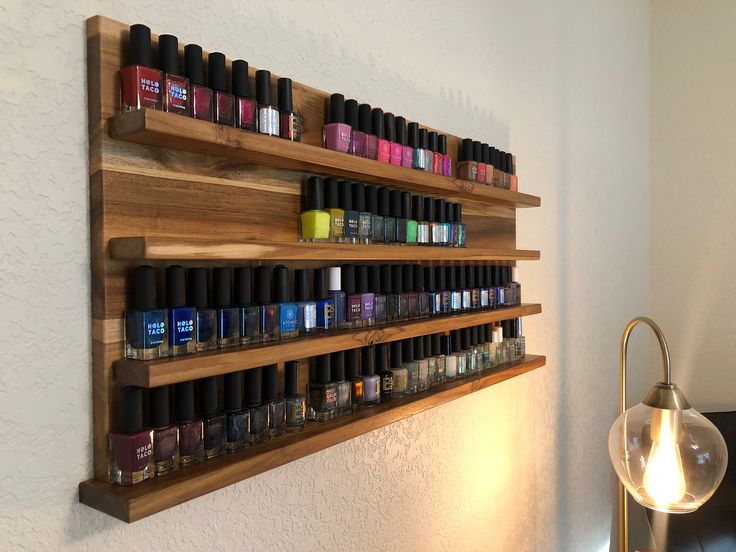 Display your nail lacquer in style with this solid teak wood wall display. Holds approximately 110 bottles of standard size nail polish, varies based on bottle size. Not a nail polish fanatic? This display can hold almost anything less than two inches deep and about three inches tall - Shot Glasses, Essential Oils, figurines, small photos, etc. This handcrafted piece is a statement piece even displayed bare, with exotic wood grain and plenty of character. Looking for a different size or wood? Ma Rustic Nail Polish Display, Nail Polish Display Ideas, Floating Nail Polish Shelves, Nail Polish Shelves Display, Professional Nail Polish Display, Nail Polish Shelves, Luxury Nail Polish, Nail Polish Shelf Wall Shelves, Nail Polish Wall Rack