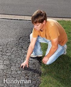 a man kneeling down on the side of a road with his hand in the ground