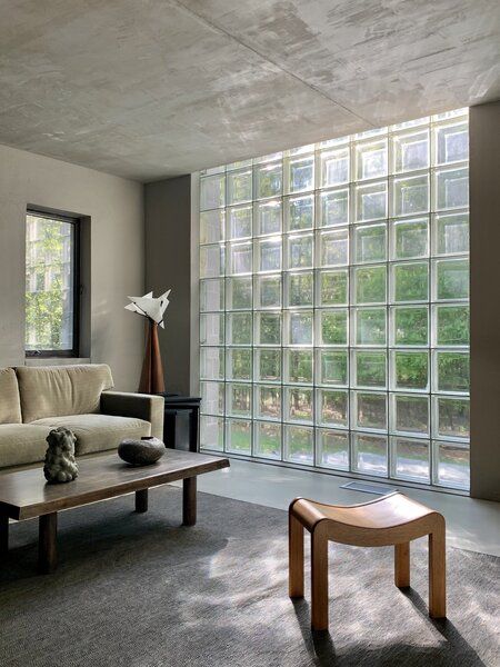 a living room filled with furniture next to a window covered in glass block wall panels