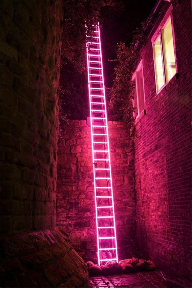 a ladder that is lit up in the dark with words above it and below it