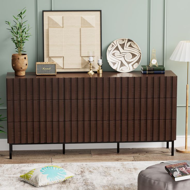 a brown dresser sitting on top of a wooden floor next to a white and green wall