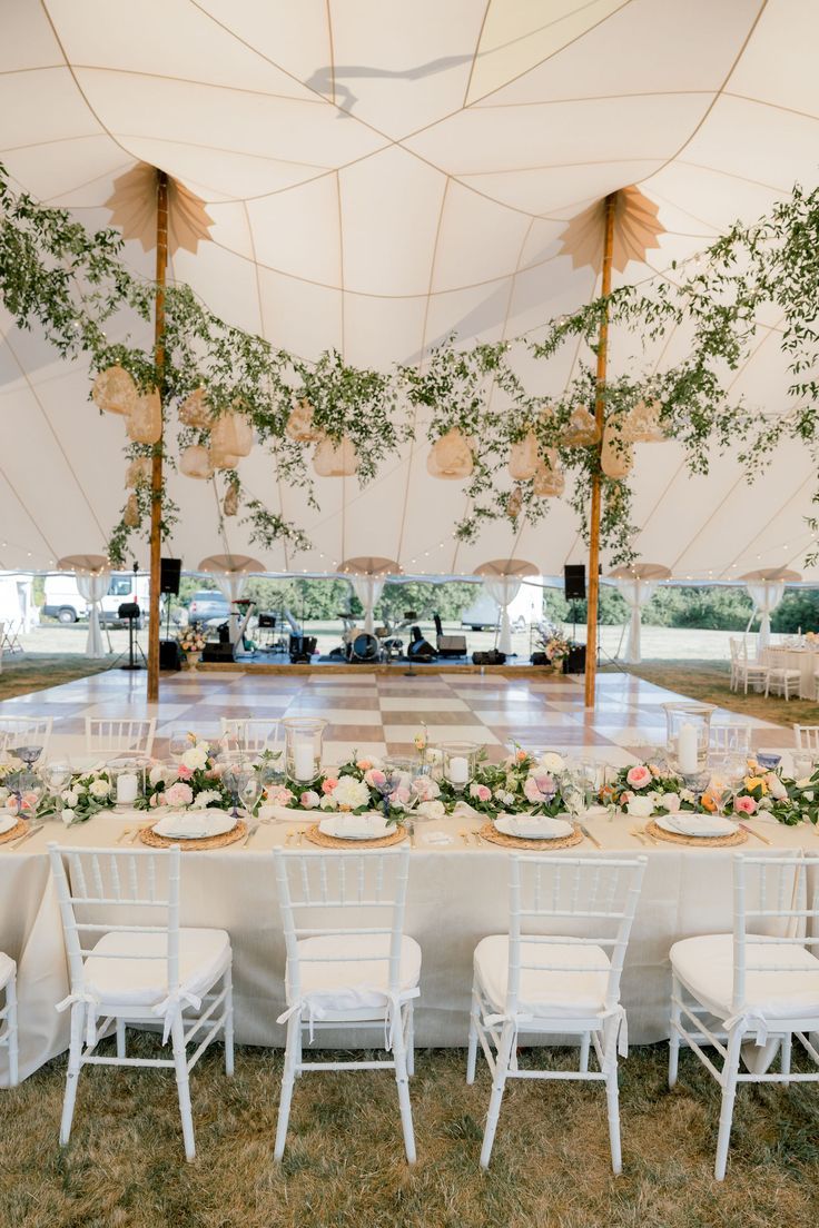 an outdoor tent with tables and chairs set up for a wedding reception