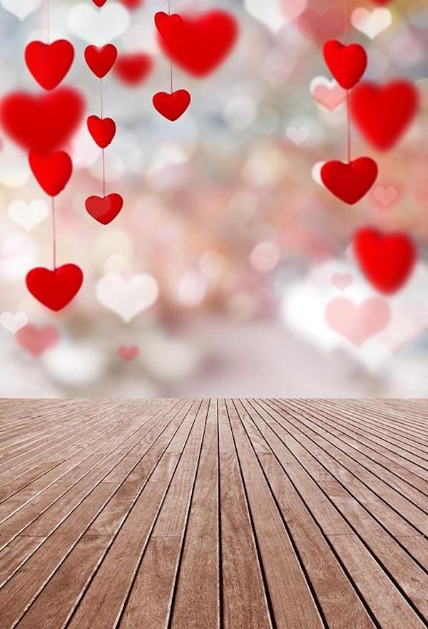 an empty wooden floor with hearts hanging from the ceiling and blurred lights in the background