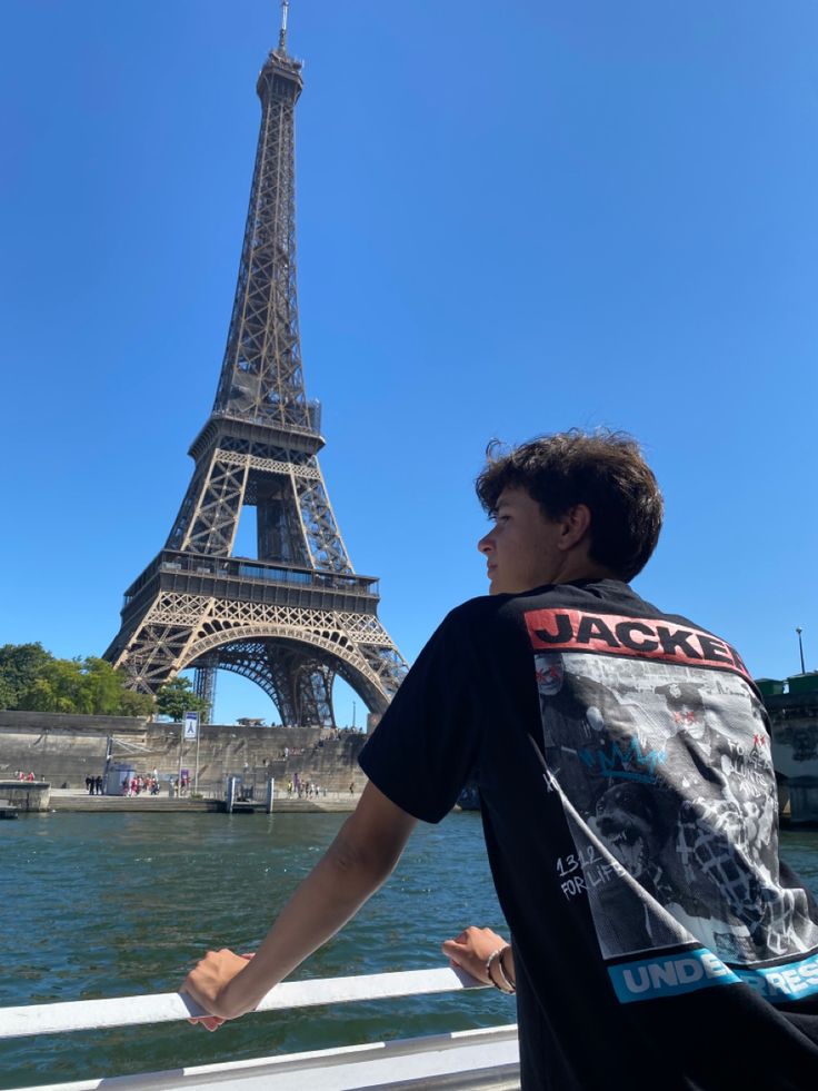 a man standing in front of the eiffel tower looking out over the water