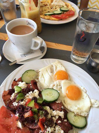 a plate with eggs, tomatoes, cucumbers, and other food on it