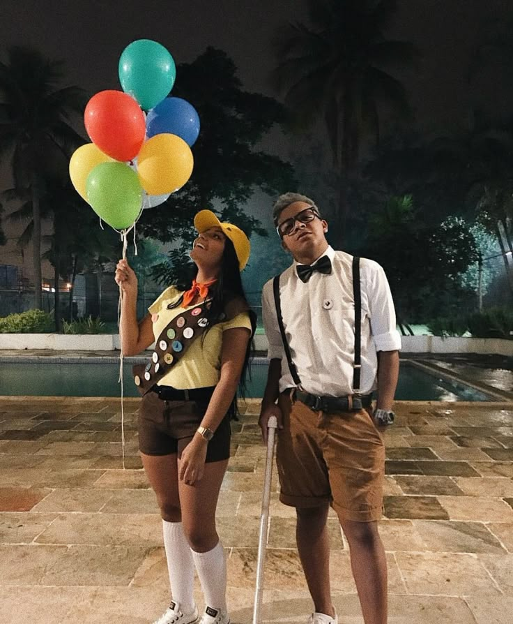 a man and woman standing next to each other holding balloons