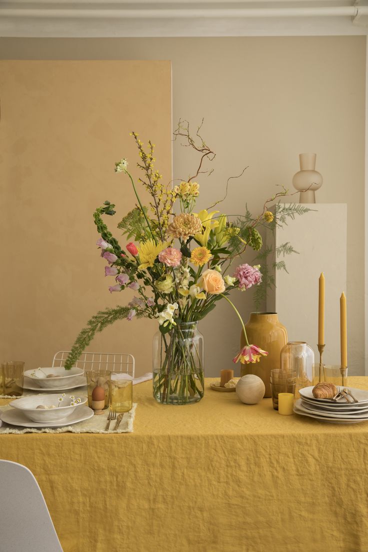 a vase filled with flowers sitting on top of a table next to plates and glasses