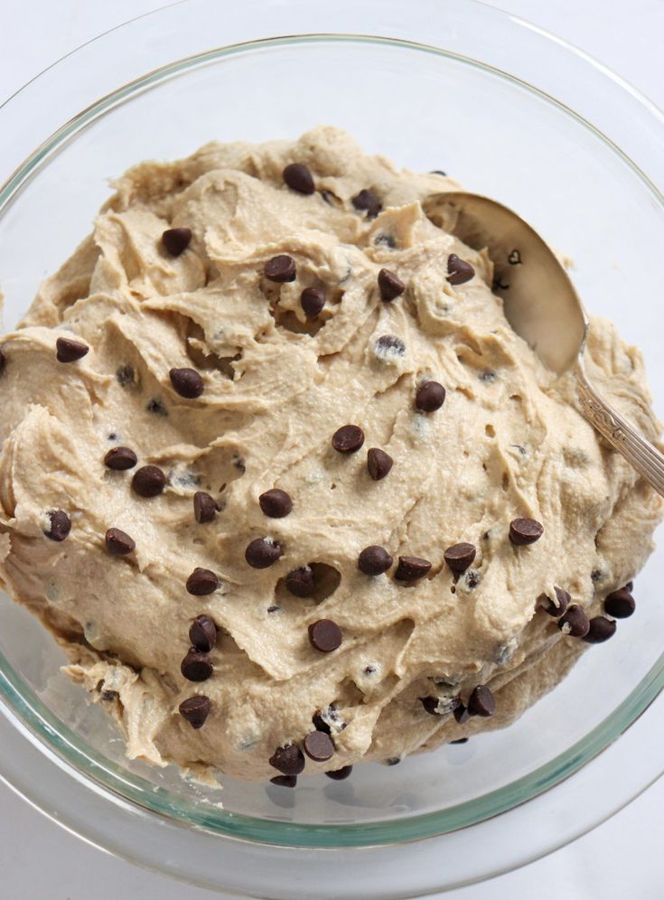 a glass bowl filled with cookie dough and chocolate chip toppings on top of it