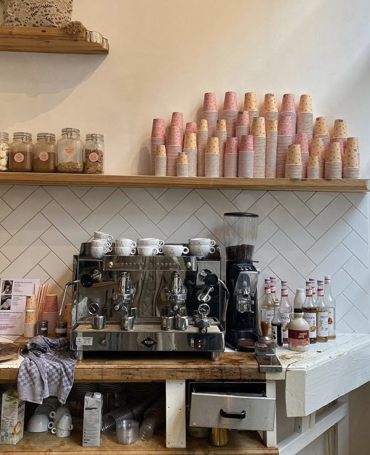 a coffee machine sitting on top of a wooden counter next to shelves filled with cups and saucers