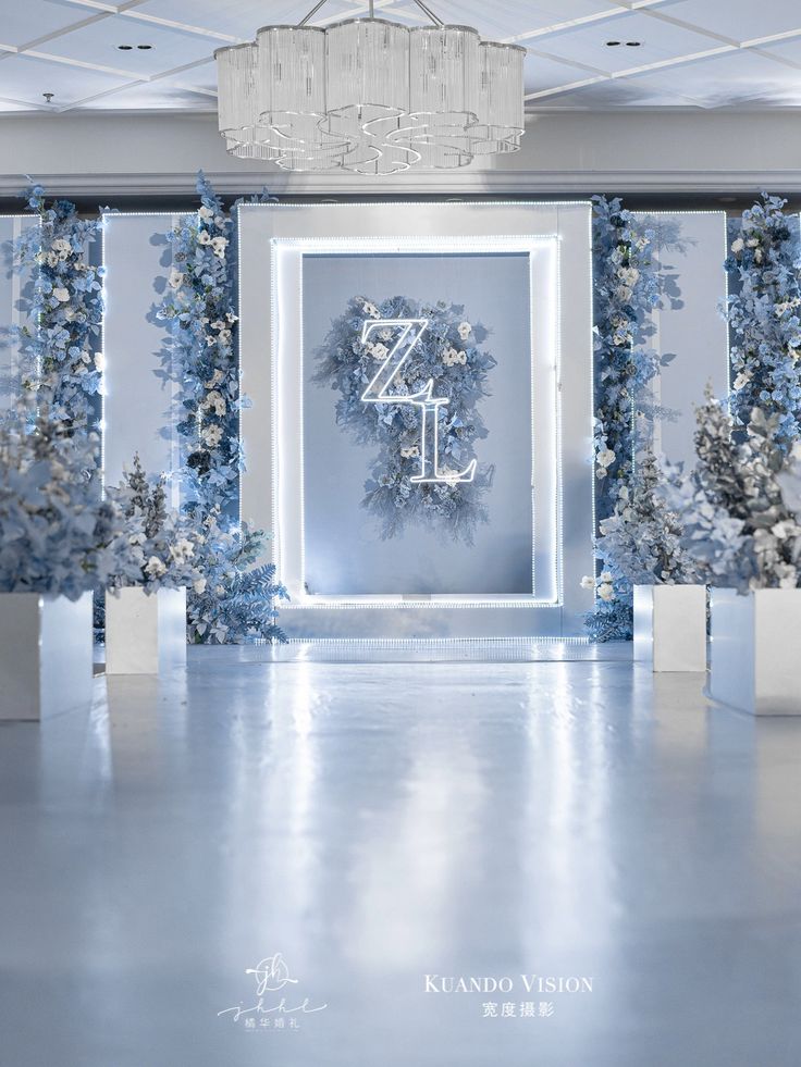 a blue and white room decorated with flowers, wreaths and chandelier hanging from the ceiling