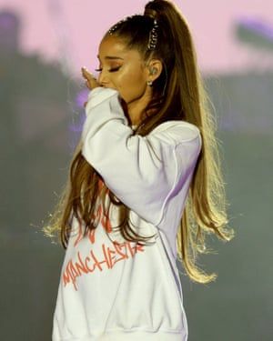 a woman with long hair standing in front of a microphone and holding her hand to her face