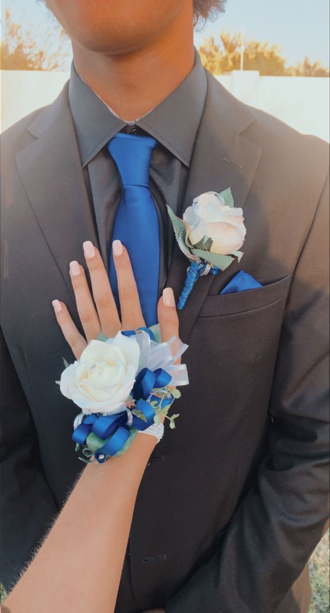 a man in a suit and blue tie with flowers on his lapel flower cuff