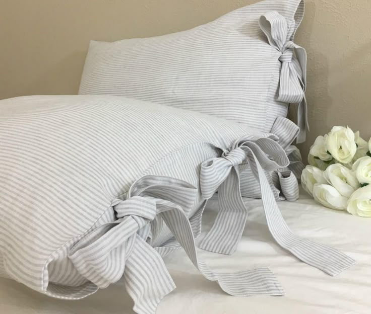 a bed with white flowers on top of it next to a pillow and some pillows