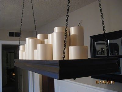 several white candles are hanging from a beam in a room with a mirror on the wall