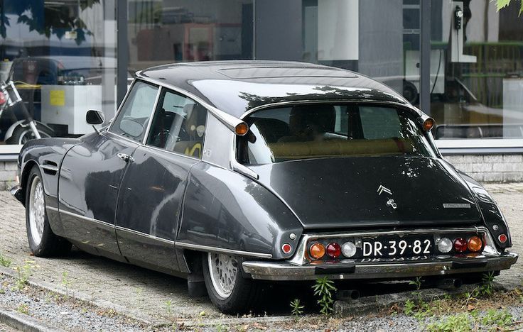 an old car is parked on the side of the road in front of a building